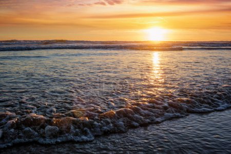 Foto de Puesta de sol en el océano Atlántico con olas crecientes en la playa de Fonte da Telha, Costa da Caparica, Portugal - Imagen libre de derechos
