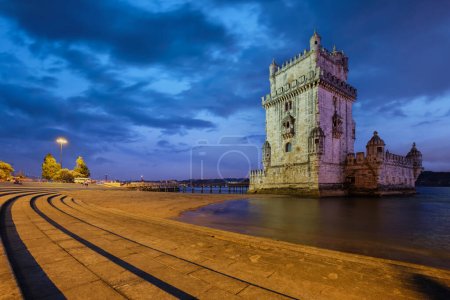 Foto de Torre Belem o Torre de San Vicente - famoso monumento turístico de Lisboa y atracción turística - en la orilla del río Tajo Tejo después de la puesta del sol en el crepúsculo con el cielo dramático. Lisboa, Portugal - Imagen libre de derechos