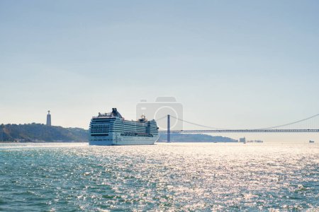 Photo for Lisbon, Portugal - August 31, 2022: MSC Orchestra cruise ship of Musica class in Tagus river with the 25 de Abril Bridge in the background. She could accommodate 2550 passengers in 1275 cabins - Royalty Free Image