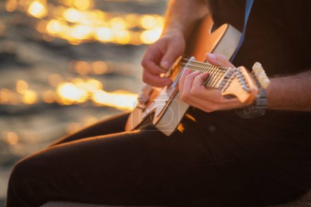 Foto de Músico callejero tocando las manos de guitarra eléctrica con la guitarra recoger de cerca con agua en el fondo - Imagen libre de derechos