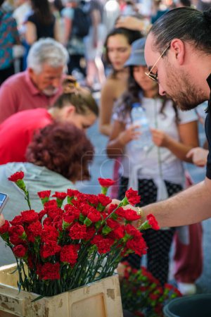 Téléchargez les photos : Lisbonne, Portugal - 25 avril 2023 : Les gens achètent des œillets lors de la célébration anniversaire de la révolution des œillets alias la révolution du 25 avril 25 de Abril par une marche de démonstration - en image libre de droit