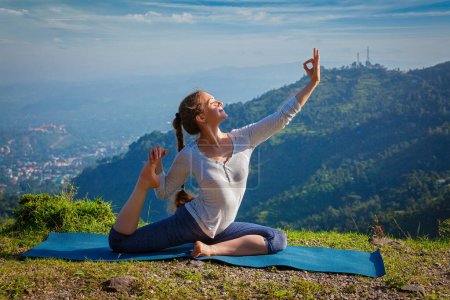Téléchargez les photos : Yoga en plein air - jeune femme faisant du yoga d'étirement asana Eka pada rajakapotasana - pose de pigeon roi à une jambe dans les montagnes de l'Himalaya, Inde - en image libre de droit