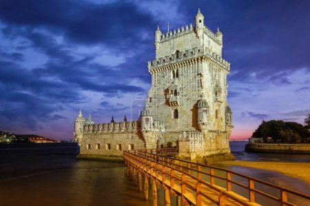 Foto de Torre Belem o Torre de San Vicente - famoso monumento turístico de Lisboa y atracción turística - en la orilla del río Tajo Tejo después de la puesta del sol en el crepúsculo con el cielo dramático. Lisboa, Portugal - Imagen libre de derechos