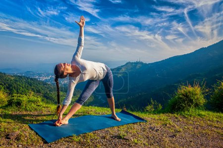 Téléchargez les photos : Femme faisant Ashtanga Vinyasa yoga asana Utthita trikonasana - triangle étendu pose à l'extérieur dans les montagnes le matin - en image libre de droit