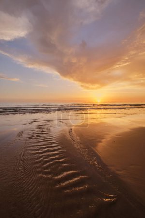 Puesta de sol en el océano Atlántico con olas crecientes en la playa de Fonte da Telha, Costa da Caparica, Portugal