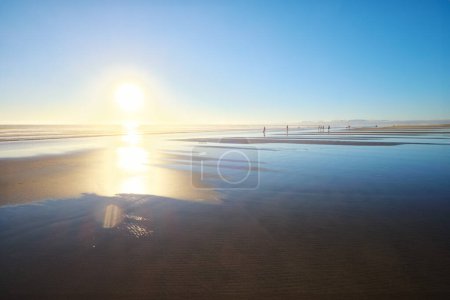 Photo for Atlantic ocean sunset with sun and surging waves at wide sand of Fonte da Telha beach, Costa da Caparica, Portugal - Royalty Free Image