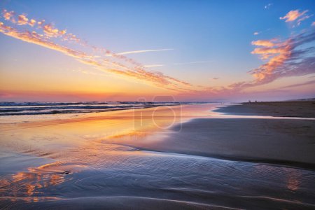 Atlantik nach Sonnenuntergang mit wogenden Wellen am Strand von Fonte da Telha, Costa da Caparica, Portugal