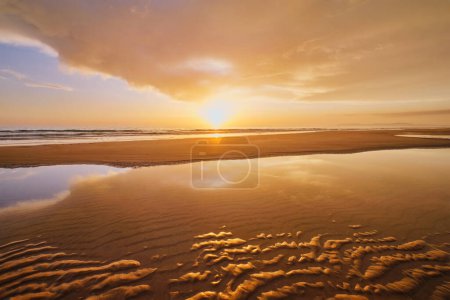 Puesta de sol en el océano Atlántico con olas crecientes en la playa de Fonte da Telha, Costa da Caparica, Portugal