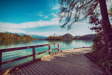 Wooden pier at Lake Bled, Slovenia with blue sky, tree and clouds in the autumn