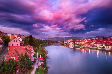 Beautiful view of Maribor city, Slovenia, at sunrise, with river and dramatic sky. Travel outdoor landscape.