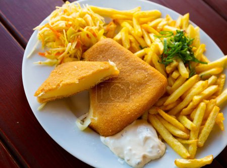 Popular plato checo de queso frito servido con papas fritas, tartar cremoso y verduras..