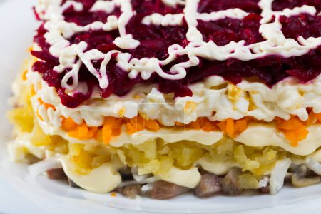Salad with layered diced pickled herring and grated boiled vegetables