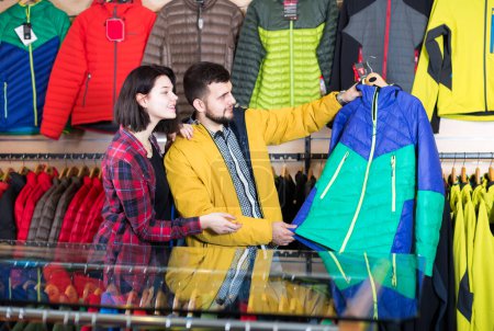 Un couple amoureux achète une veste de sport dans un magasin de vêtements