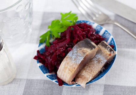 Sliced herring with beetroot served table. Chopped fish with grated beet on table.