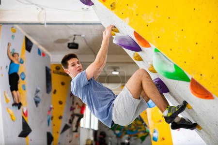 Sportliches Männertraining in Boulderhalle ohne spezielle Kletterausrüstung