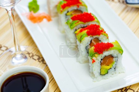 Tasty uramaki sushi with salmon, mango, avocado and cucumber served at plate