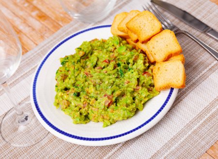 Just cooked guacamole on table with bunch of dry bread.