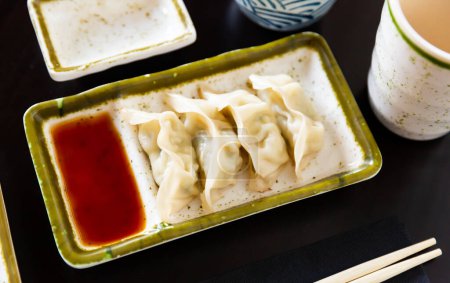 Service plate containing traditional steamed Yaki Gyoza with mixed soya sauce