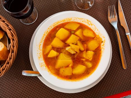 Restaurant serviert Gericht aus Kartoffelkompott mit Tintenfisch. Gemüseeintopf aus Kartoffeln, grünen Erbsen, Karotten und Schalentieren.