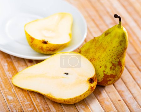 Juicy ripe pears, whole fruits and cut in half are on plate. Vitamin snack, healthy food, healthy lifestyle concept