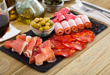 Köstliche Fleischplatte - in Scheiben geschnittene trockene Marmelade, Speck, Chorizo und Salami auf Schieferplatte mit Oliven ..