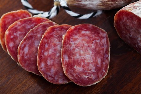Traditional Catalan dry cured pork sausage Longaniza with sliced pieces on wooden board..