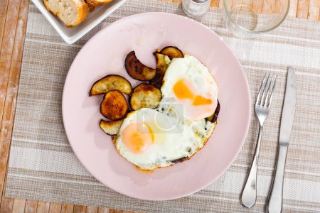 Image of a appetizing fried eggs, cooked with sliced roasted eggplant