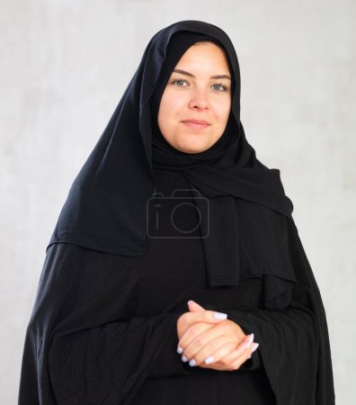De cerca portret de mujer musulmana joven con hermosa sonrisa aislada en la pared gris.