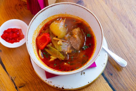 Oriental Lagman soup with lamb and vegetables on a wooden table in a restaurant