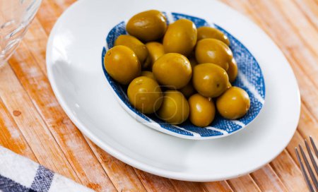 Portion ganze marinierte Oliven mit Kernen auf Teller serviert.