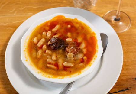Asturian fabada soup with white beans and blood sausage served in bowl
