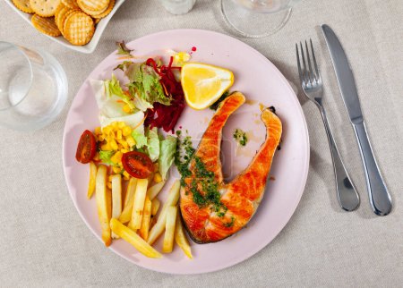 Delicious grilled salmon fillet with a side dish of baked potatoes, corn, lettuce and beets