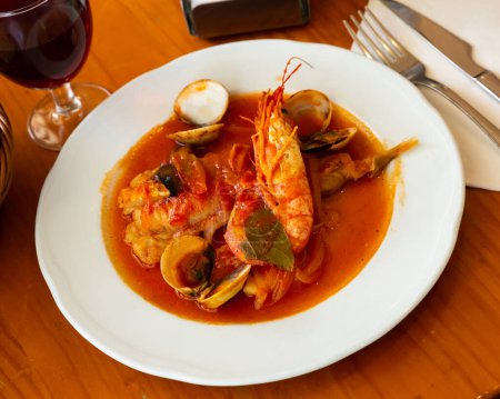 Gourmet seafood tapas. Delicious monkfish tail stewed in tomato sauce with clams and shrimps