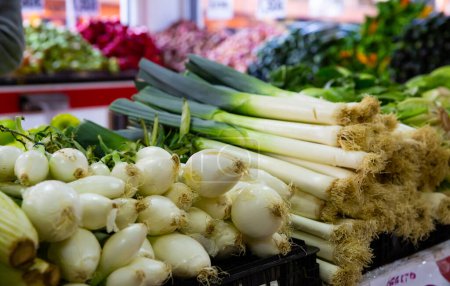 Fresh green spring onion and leek on counter of farmer market ..