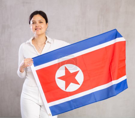 Portrait of positive young woman with the flag of North Korea