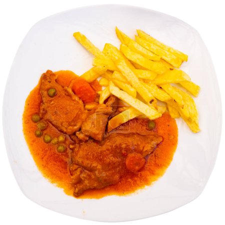 On round white plate are pieces of roast veal tenderloin with green pea in tomato sauce. Dish garnished with French fries. Isolated over white background