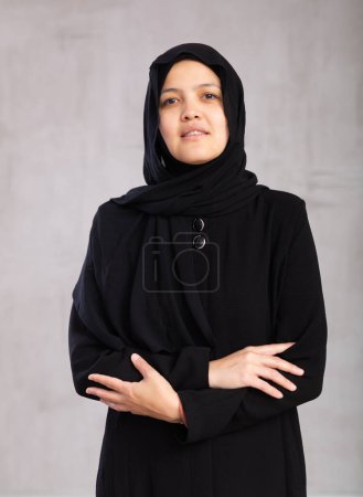 Portrait of young positive woman in hijab posing on studio background