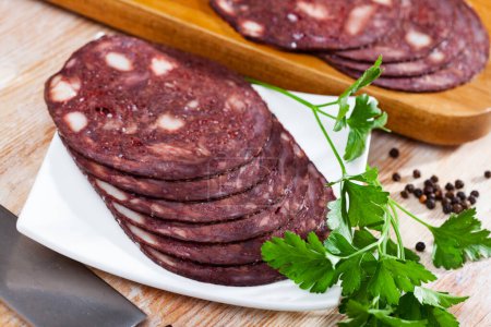 European cuisine blood pudding served with parley on white plate on wooden table