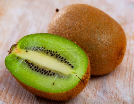 Frische saftige ganze und halbierte Kiwi-Früchte auf einem Holztisch. Gesundes Vitaminprodukt