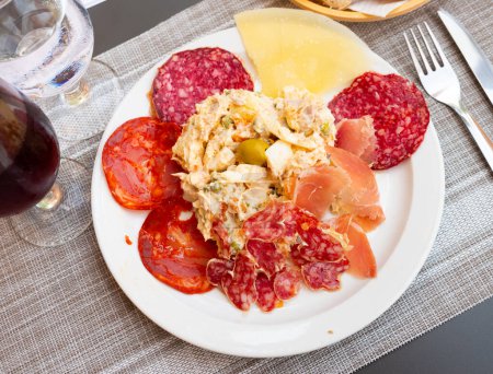 Traditional Spanish appetizer Entremeses, cold cuts of various sausages, jamon and cheese slices served with Russian salad