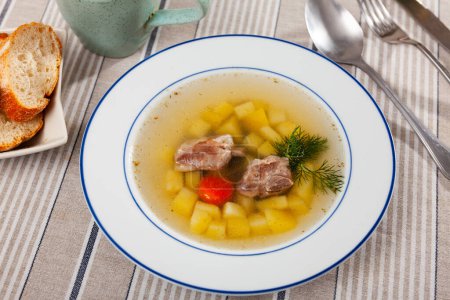 Soupe appétissante au bouillon de porc avec pommes de terre, carottes et oignons assaisonnés d'herbes. Réconfort alimentaire .