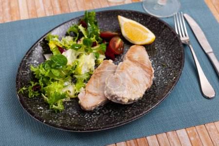 Scandinavian cuisine seafood served with greens and vegetables on plate on wooden table