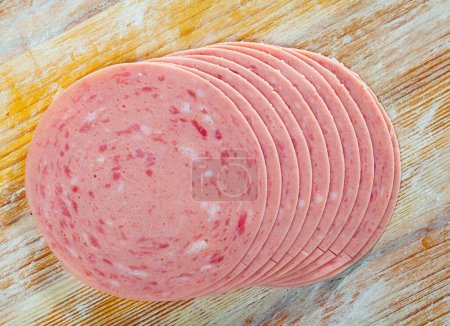 Traditional cooked sausage from chopped pork meat thinly sliced on wooden table