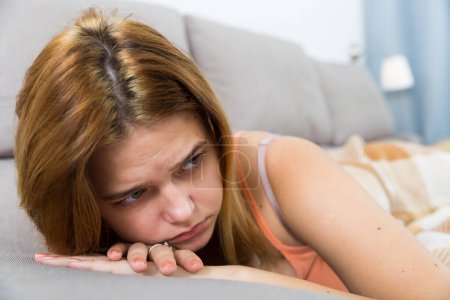 Joven mujer triste sentado en el sofá acogedor y la melancolía en casa