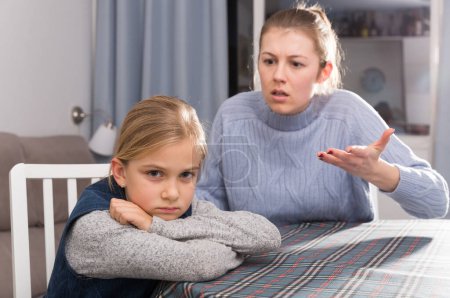 Young woman scolding her daughter at home interior