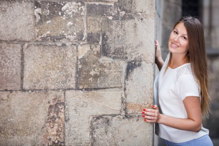 Romantic girl peeking out from behind cathedral wall looking at camera, copyspace