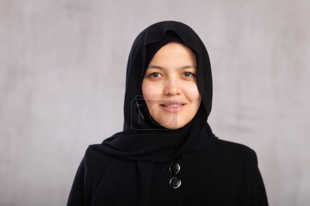 Positive junge muslimische Frau trägt einen Hidschab und schaut in das Kamerastudio