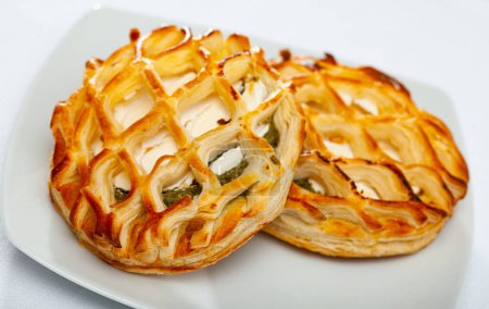 Crisp puffs filled with spinach and soft goat cheese on plate. Traditional pastries