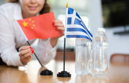 Junge Assistentin setzt griechische und chinesische Flaggen für internationale Verhandlungen