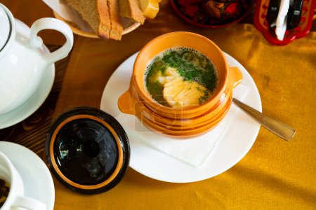 Sopa de oreja apetitosa con hierbas en una olla de barro